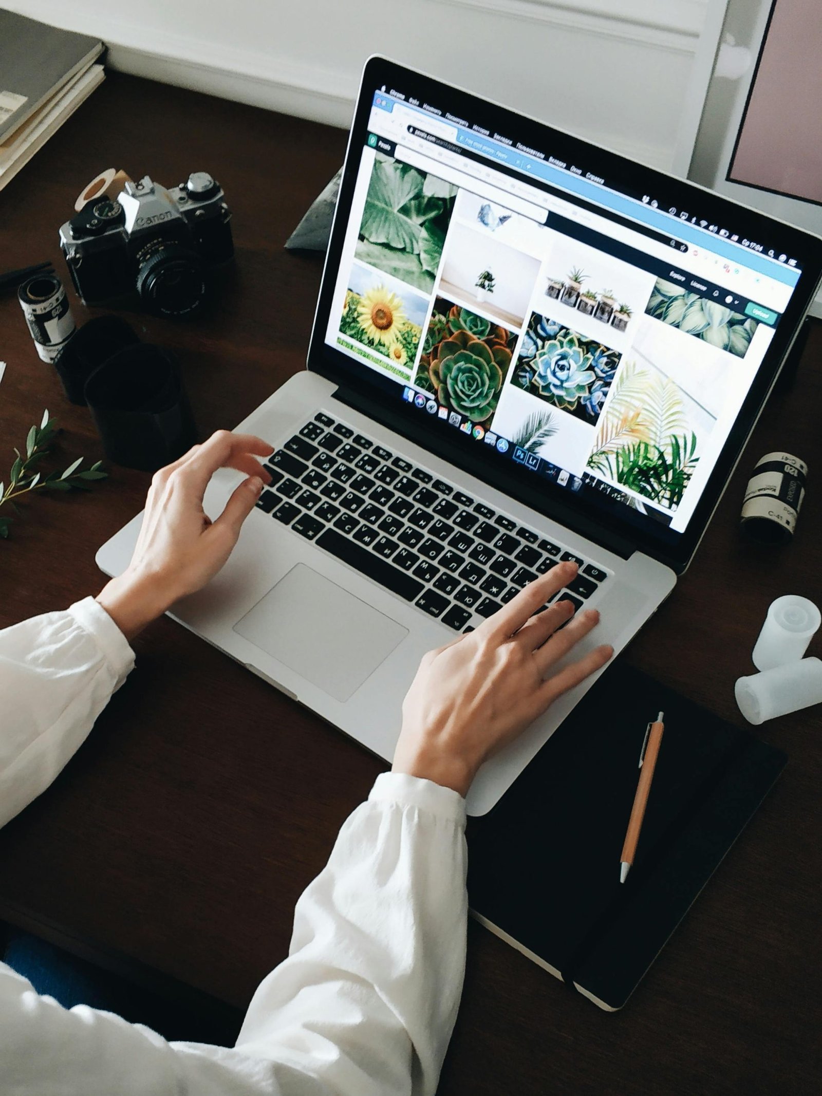 Services Person working on laptop with film camera nearby. Perfect for technology and lifestyle themes.